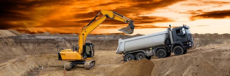 Excavator loading dump truck at quarry site
