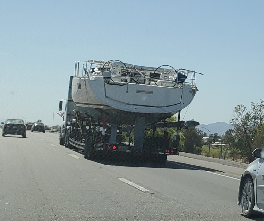 Large sailboat on trailer truck transported on highway